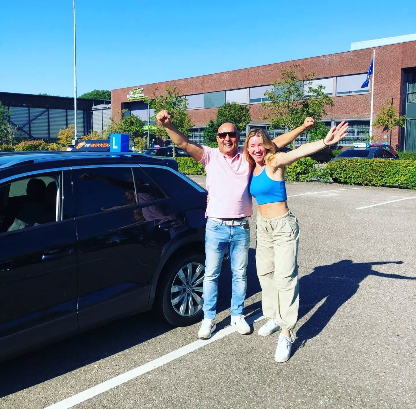 Geslaagde leerling en instructeur bij de lesauto van De Rijdocent
